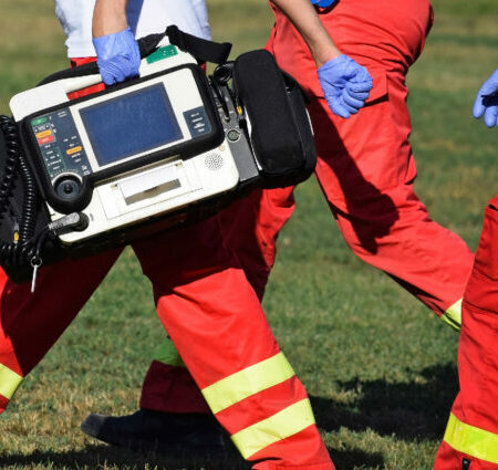Emergency Services workers carrying a defibrillator